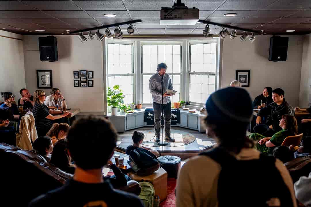 A poet in front of crowd in a coffeehouse for a reading