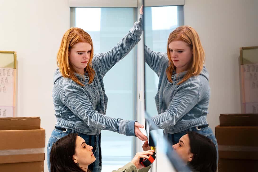 Two women hang a painting in an art museum