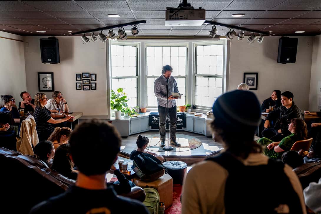 A poet in front of crowd in a coffeehouse for a reading