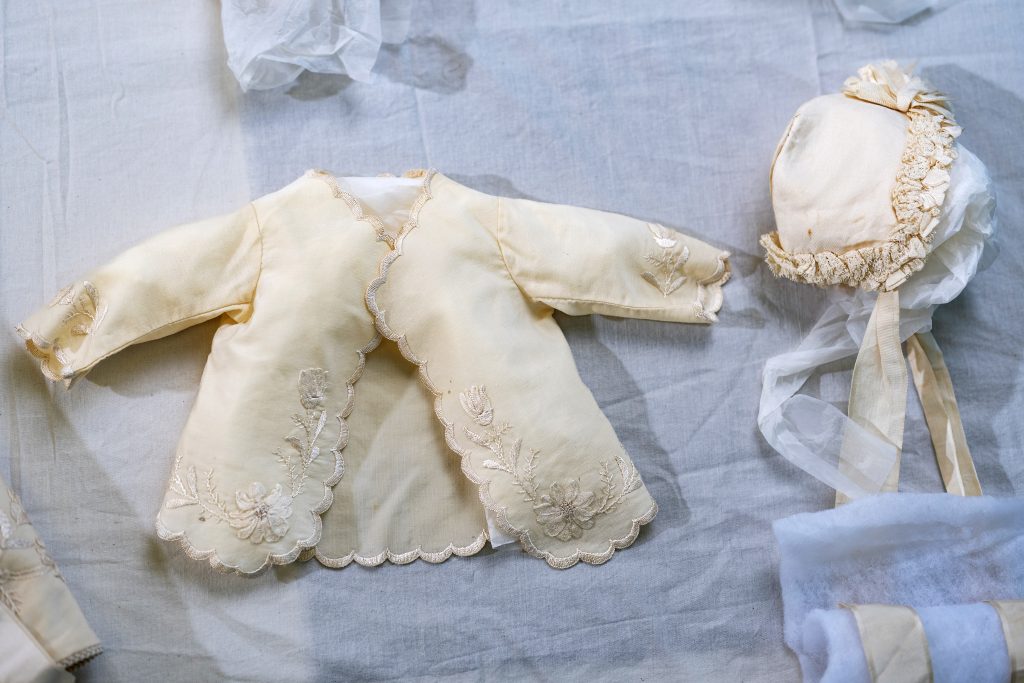 Two pieces of a delicately embroidered baptismal ensemble.
