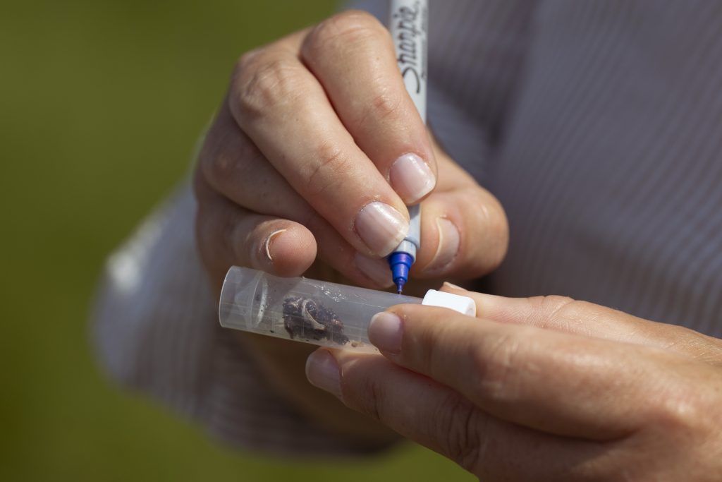 A person writes on a plastic cylinder. 