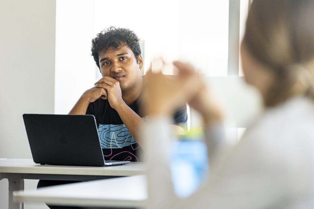 A student looks thoughtful as he sits at a computer.