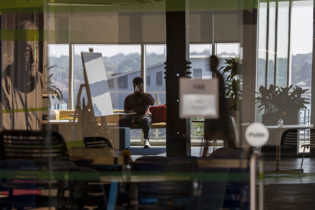 A student sits in front of a backdrop of windows.