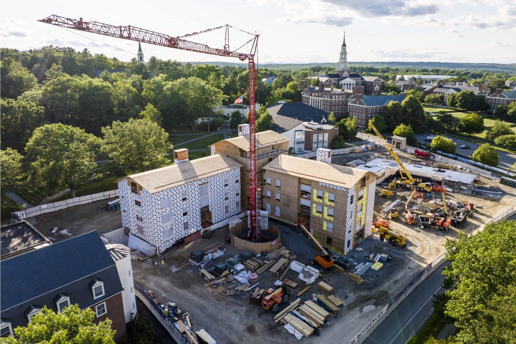 A large campus building being constructed with a tall crane next to it.