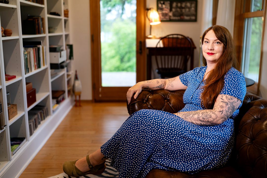 A person sits in a chair and looks at the camera.