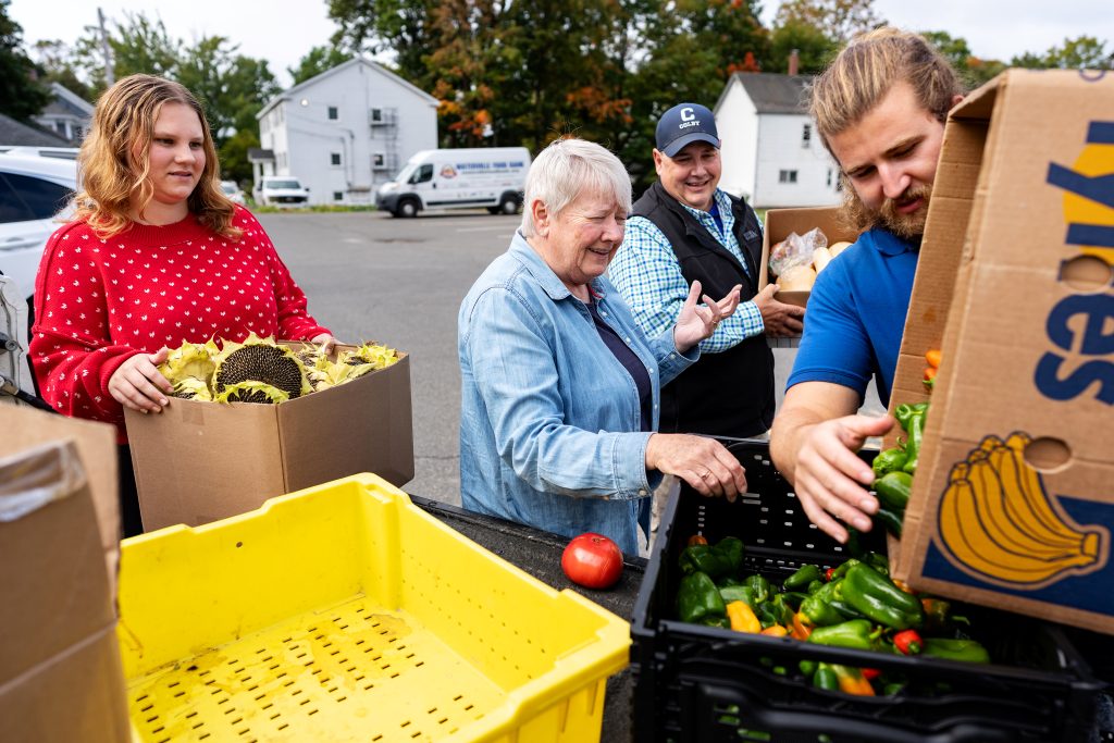 A student and staff make a donation of fresh vegetables to the Waterville Food Bank. 
