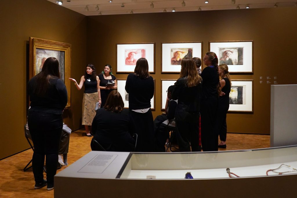 A group of people standing around a painting in a museum.