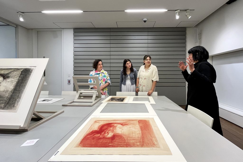 A group of people standing around a table with artwork on it.