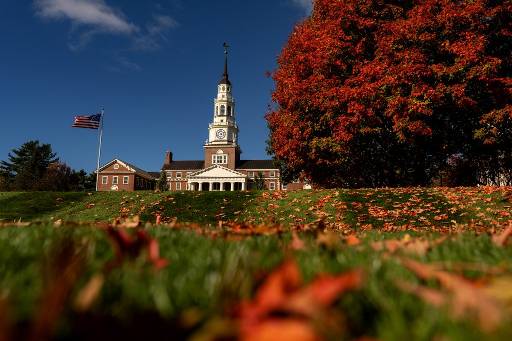 A view of Miller Library during autumn with orange leaves strewn across the lawn.