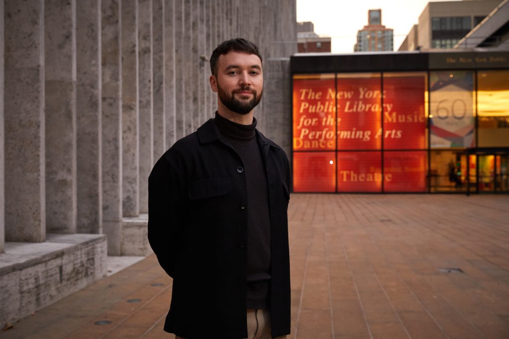 A man stands in front of the New York Public Library for the Performing Arts