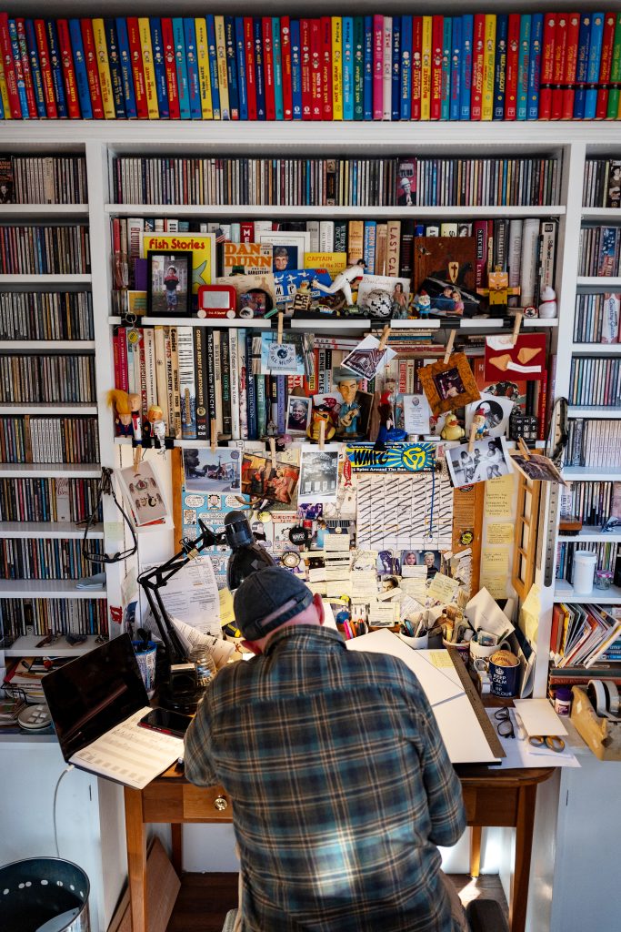 The rear view of a man drawing at a desk.