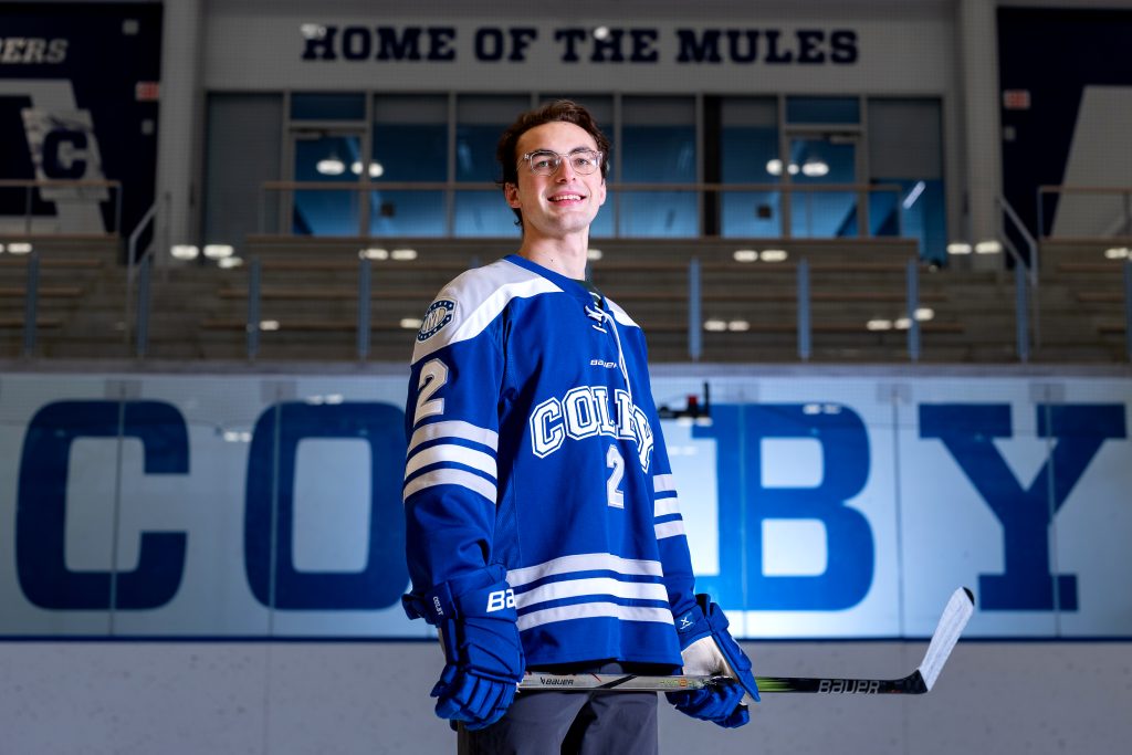 A Colby hockey player in gear poses for a photo.