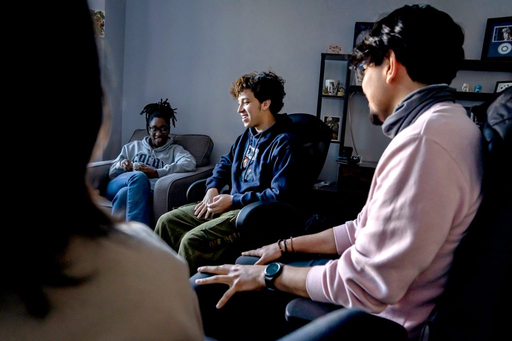 Three college students sit in a circle for a discussion.