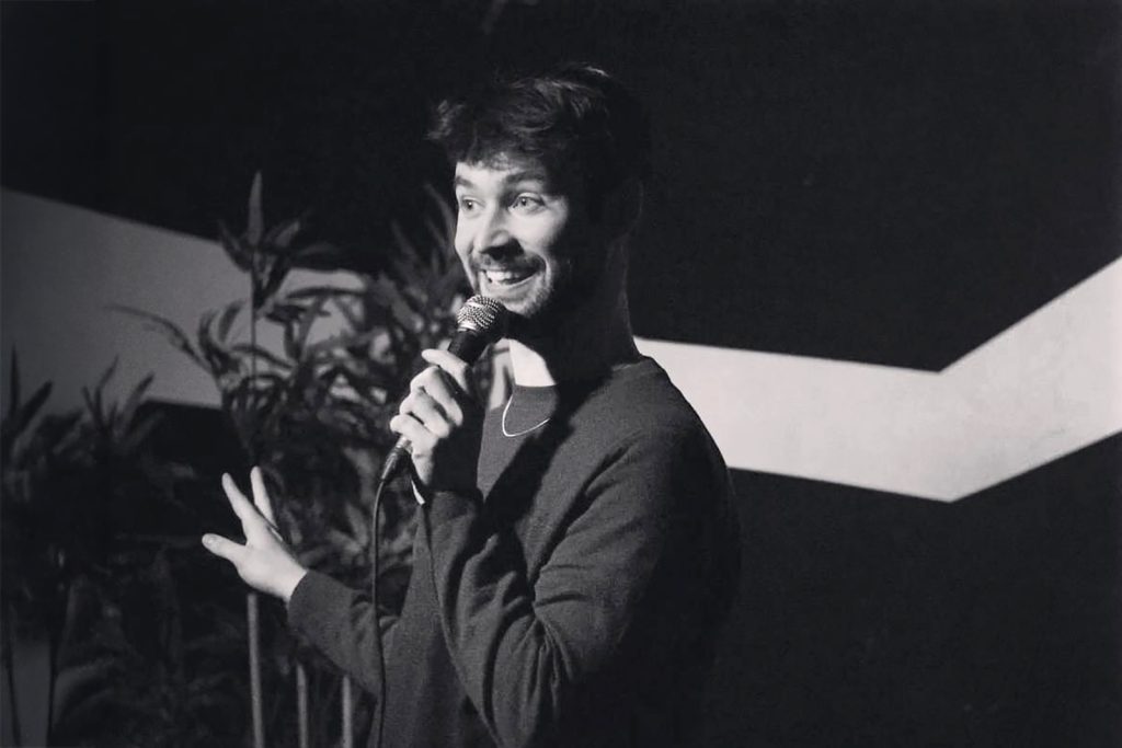 A man smiles behind a microphone
