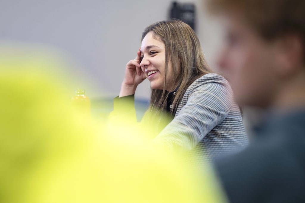 A smiling student sitting at a table.