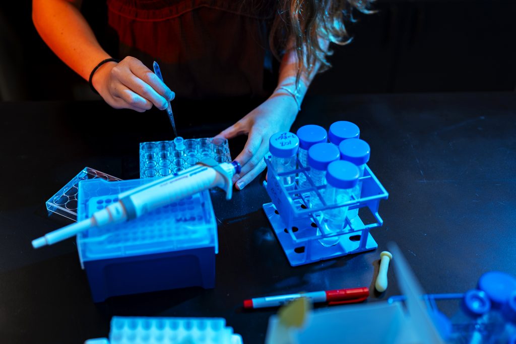 A student's hands are seen working with beakers and test tubes. 
