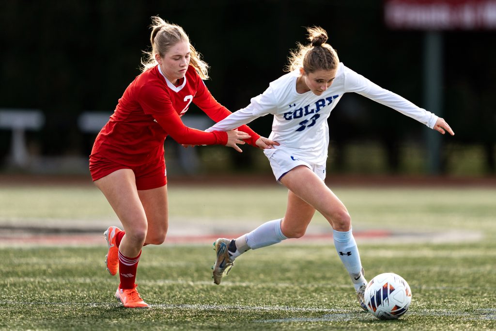 A defending soccer players chases a Colby player advancing with the ball.