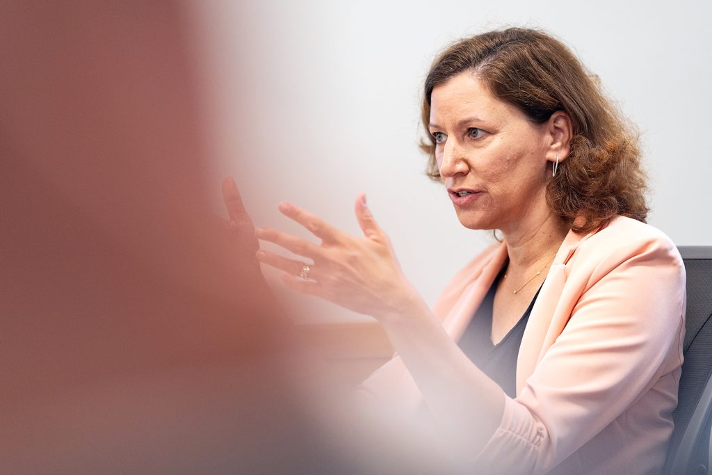 A sitting woman raises her hands while talking.