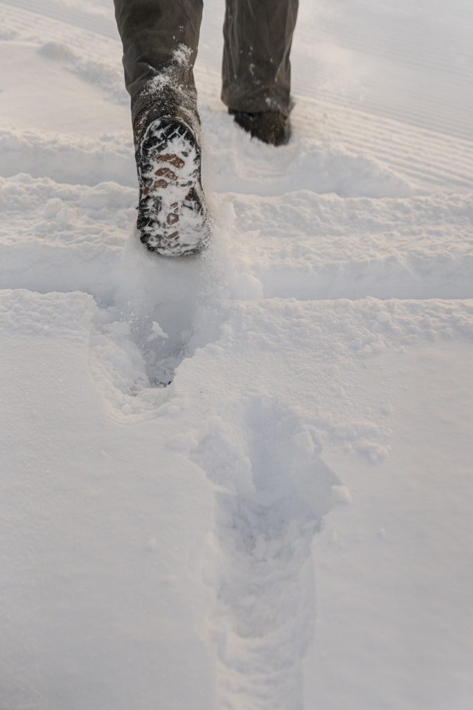 Two feet walking through powdery snow.