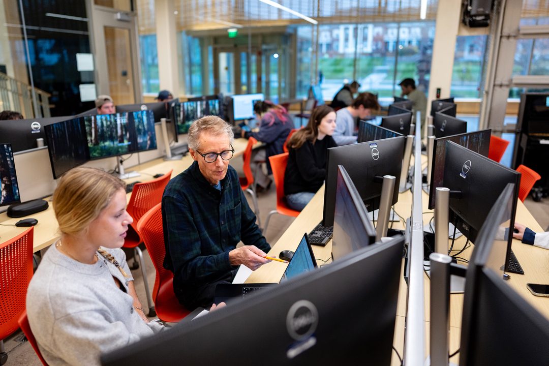 Male college professor working with a student at a computer