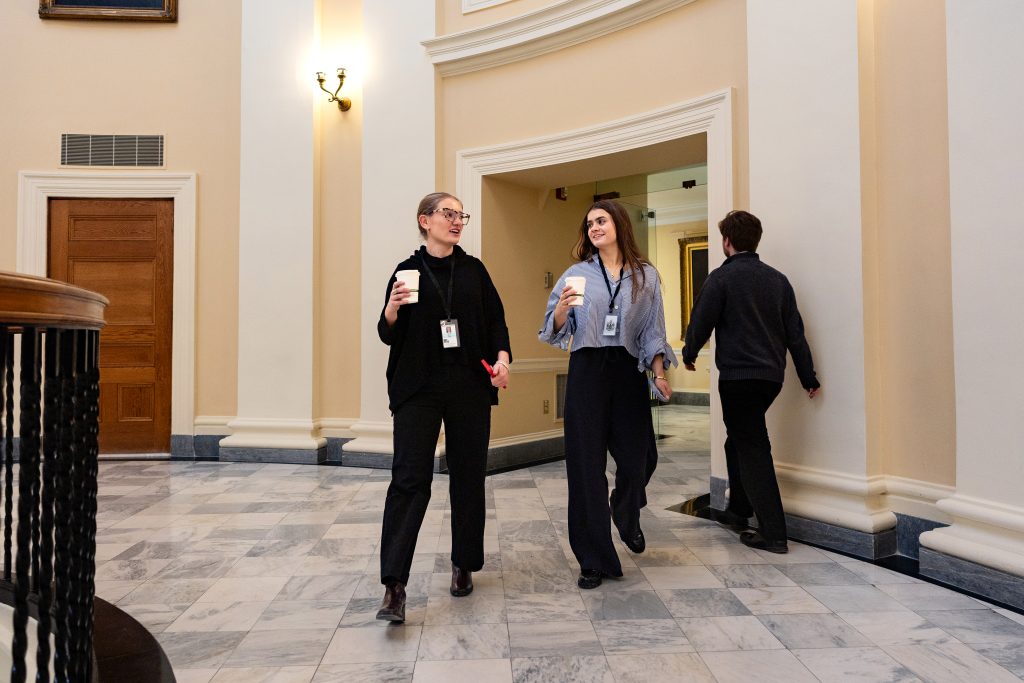 Two students walk through the Maine State House. 