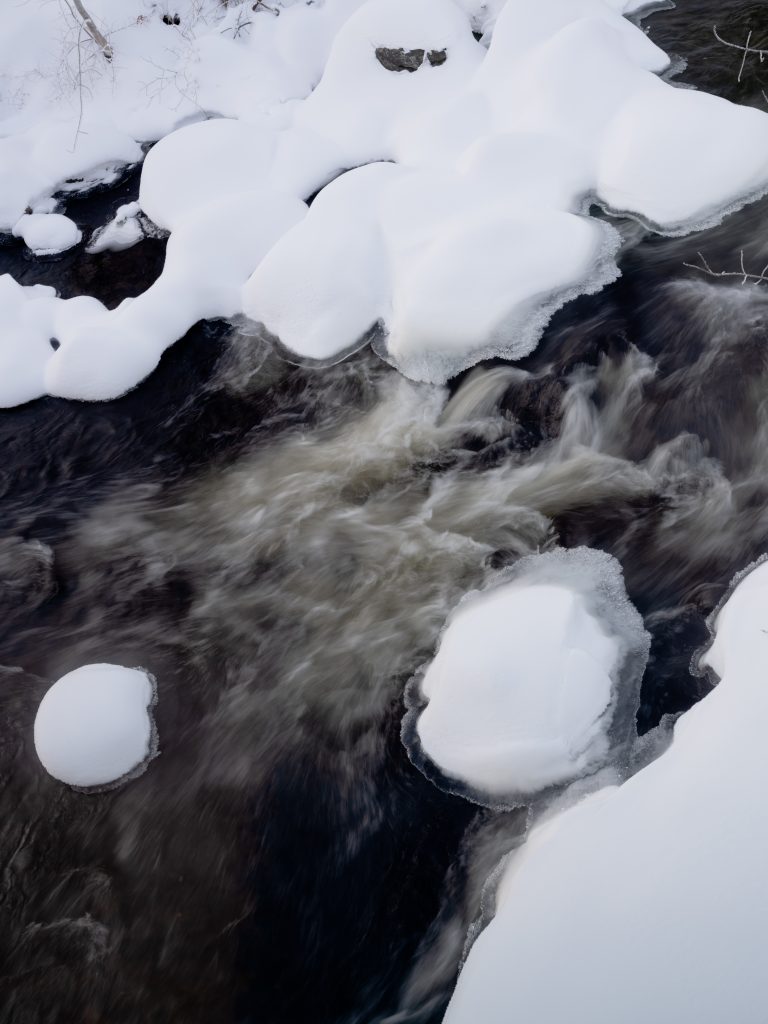 Photo of turbulent river water with snow and ice
