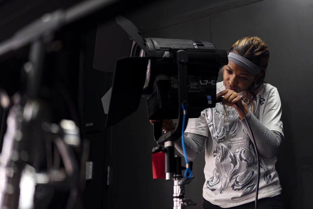 A student sets up lighting equipment. 