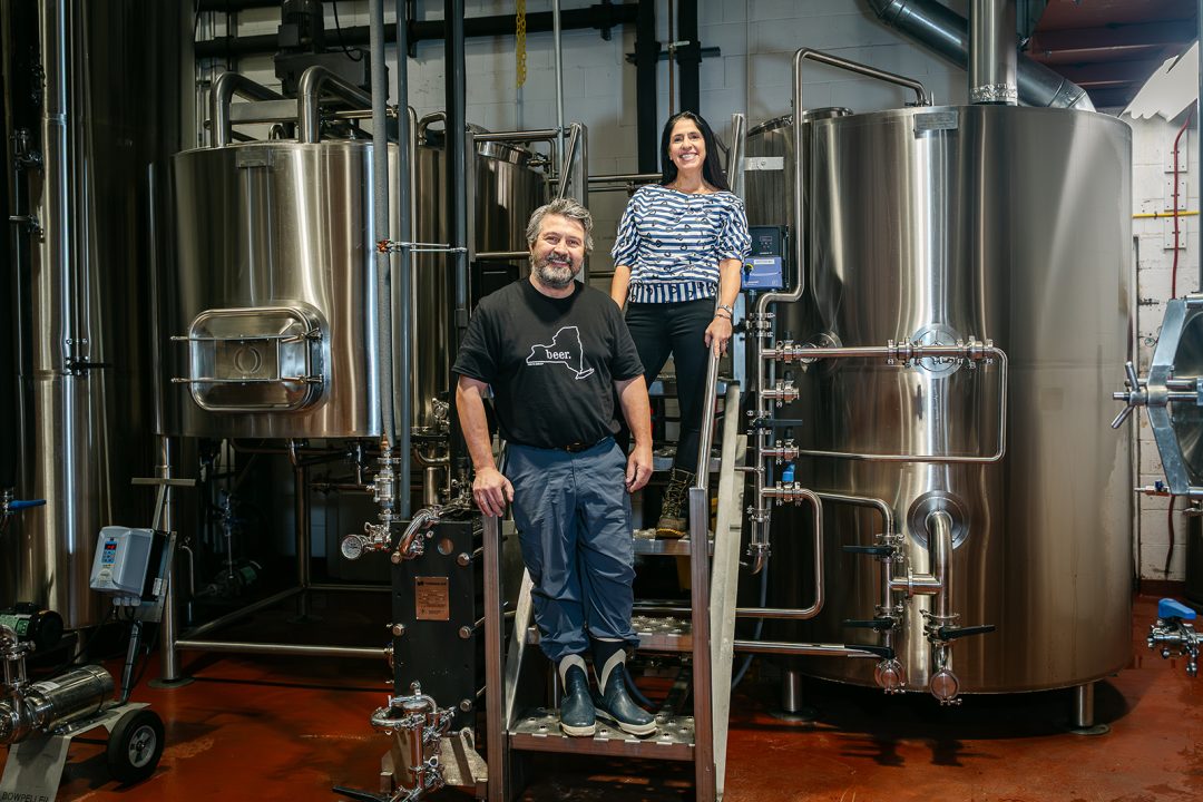 Two people stand inside a brewery.