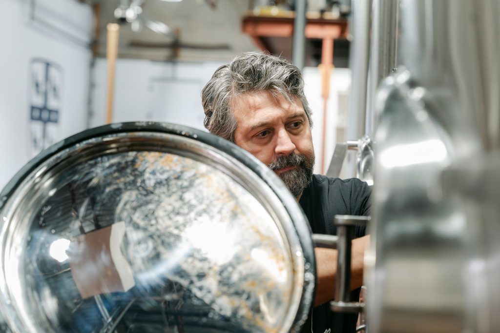 A man uses brewing equipment.