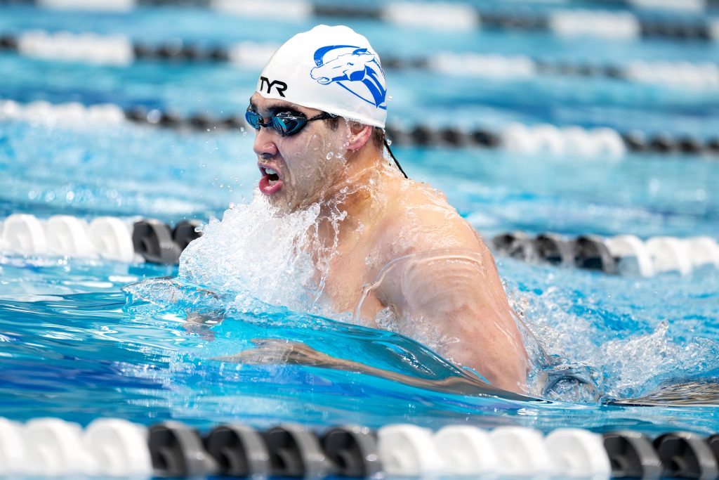 A swimming athlete emerges from the water.