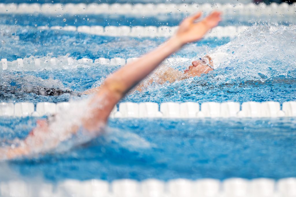 An arm emerges from the water of an indoor pool.