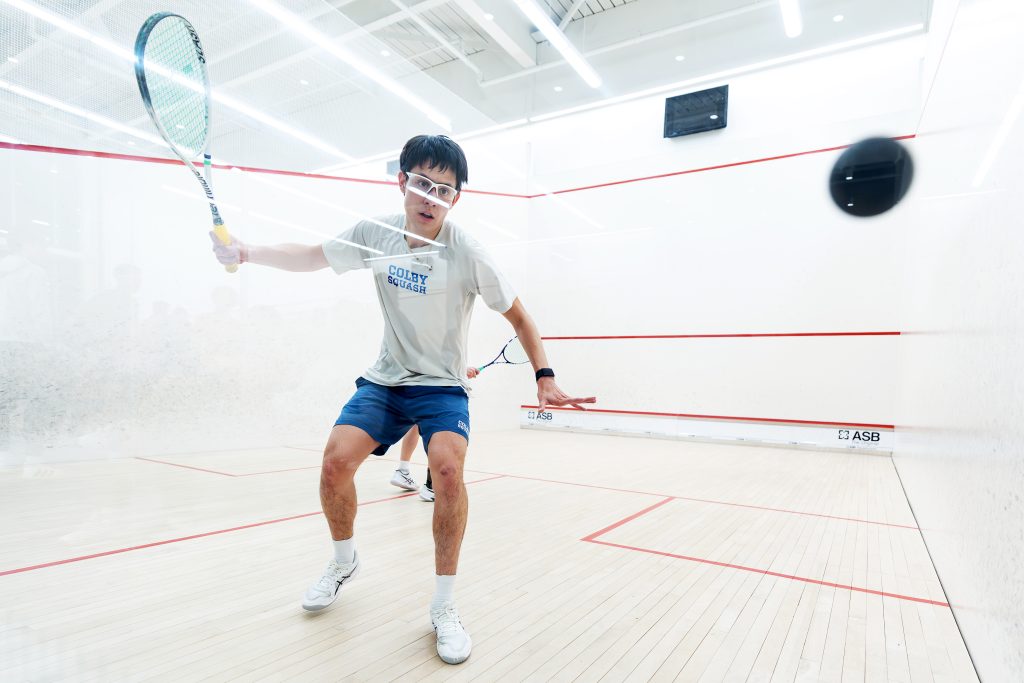 A squash player about to hit the ball with his racket.