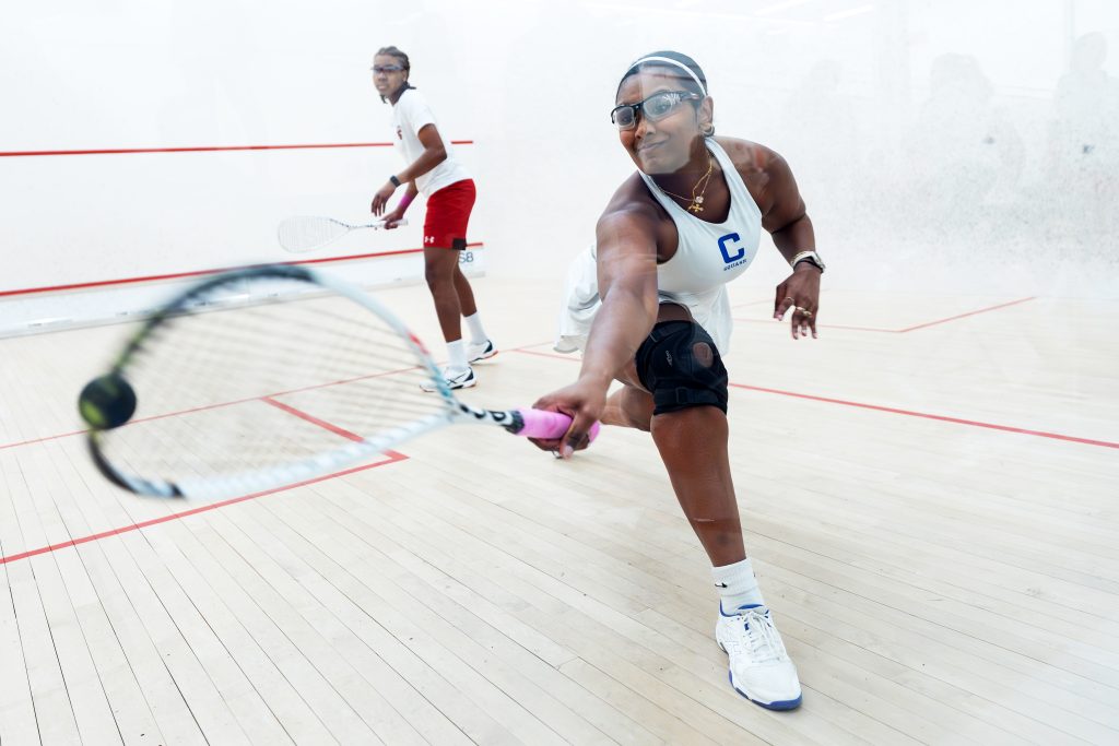 A squash player lunging into view with their racket.