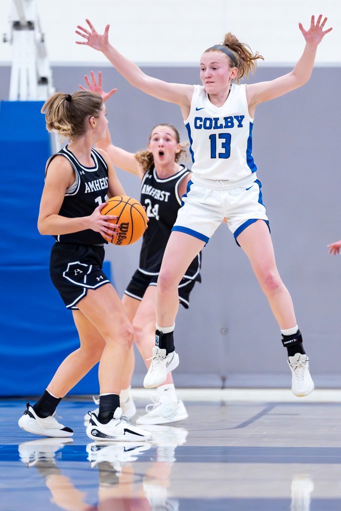 A Colby basketball player attempts to block a rival player holding the ball.