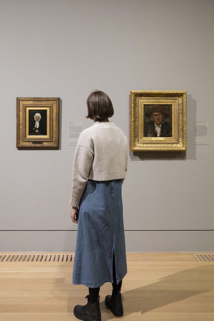 A person at an art museum looks at two paintings.