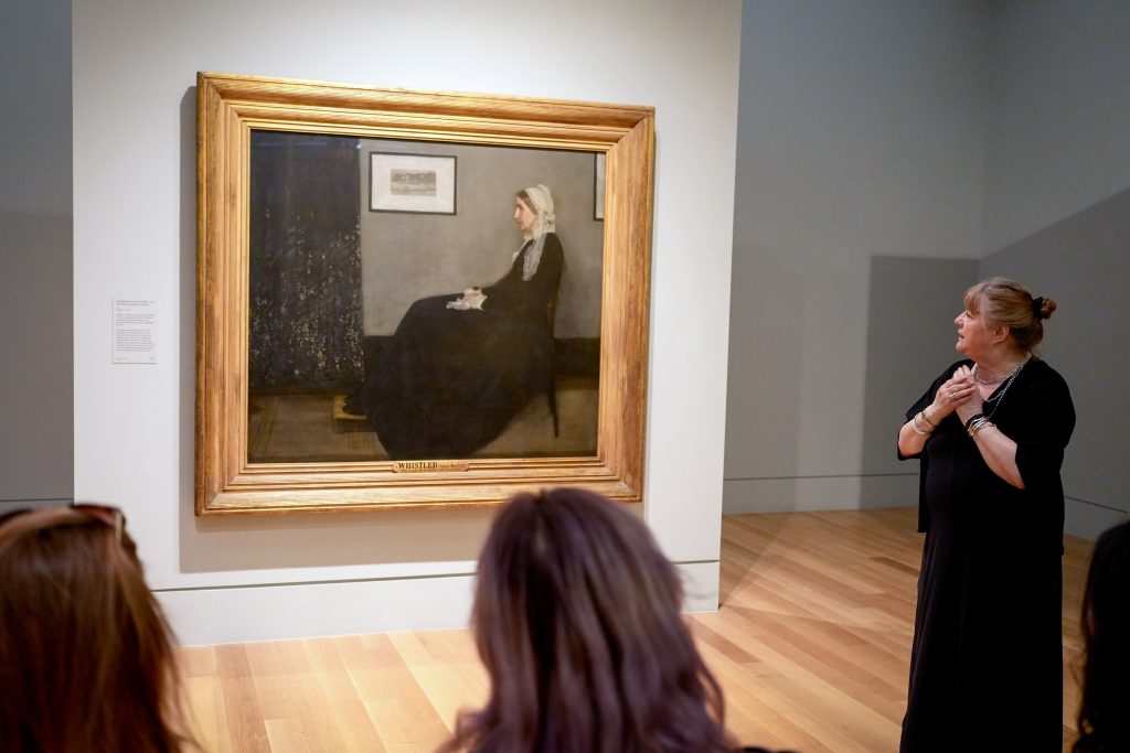 People at a museum look at a painting together.