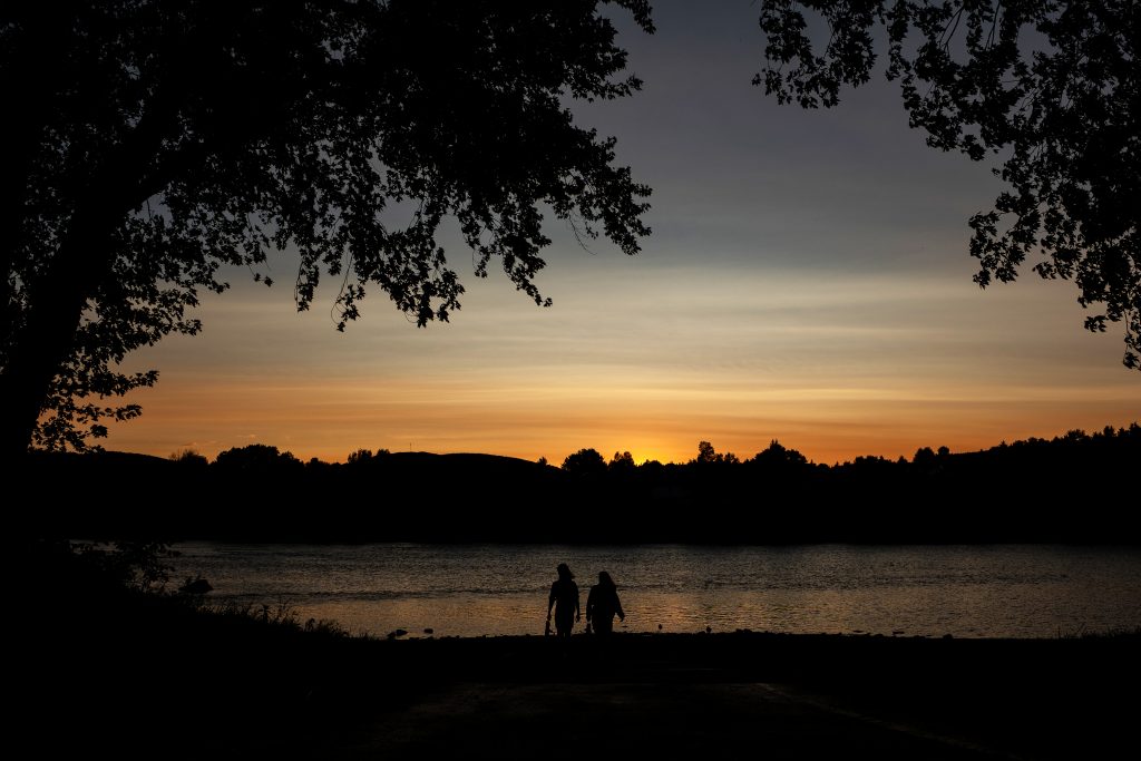 Students silhouhetted against a river with the setting sun in the background