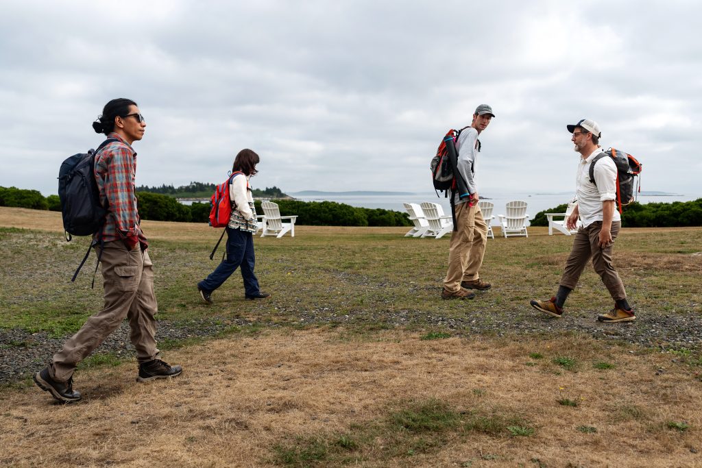 People wearing backpacks walk on Allen Island. 