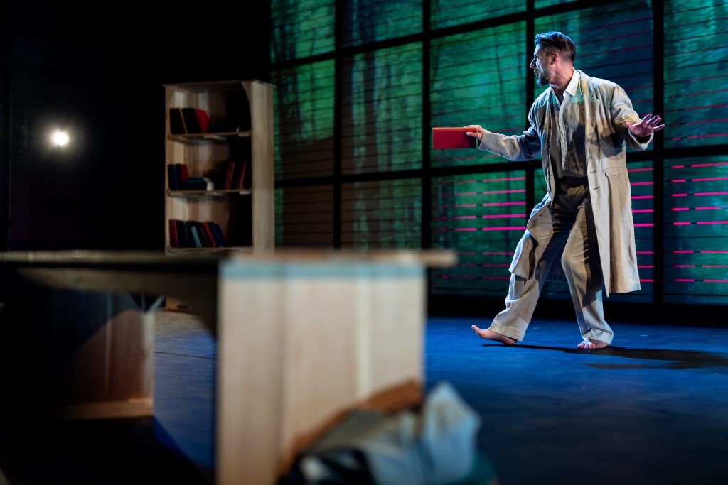One man moves around a stage. 