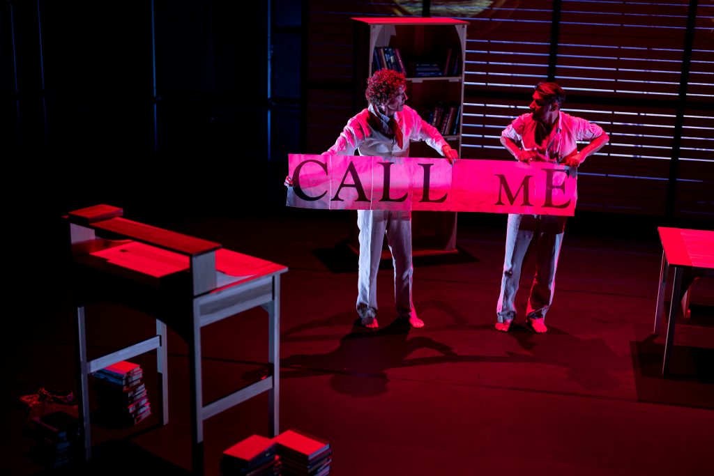 Two men unfurl a banner on a stage. 