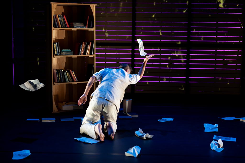 One man crouches on a stage. 