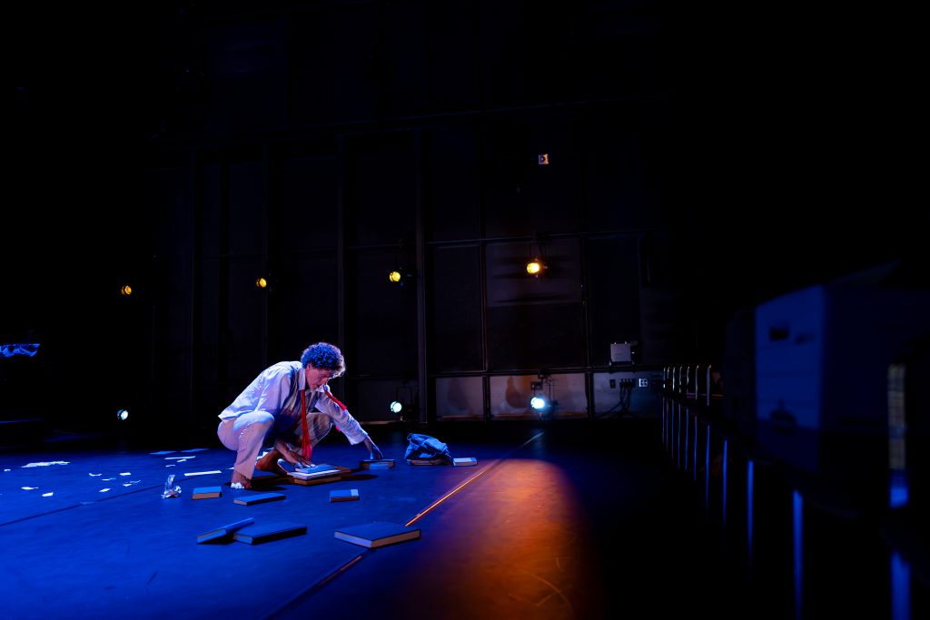 One man crouches on a stage. 