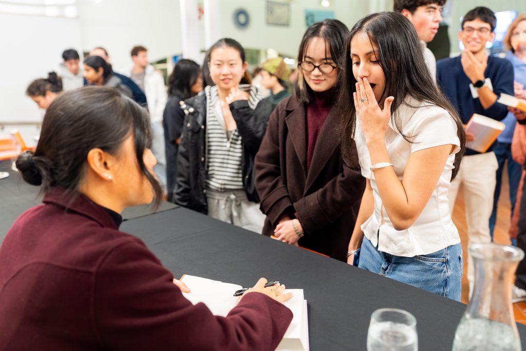An author signs books for students. 